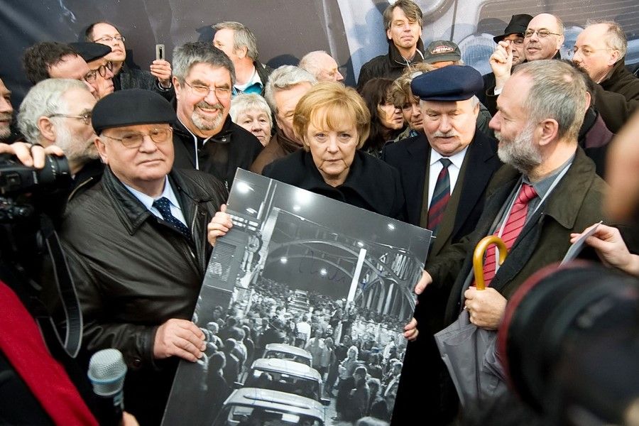 In this file photo taken on 9 November 2009 former Russian President Mikhail Gorbachev (left), German Chancellor Angela Merkel (centre) and former Polish President Lech Walesa hold a signed print of people crossing the Boesbrucke border bridge as they crossed the same bridge during a ceremony to mark the 20th anniversary of the fall of the wall in Berlin. (Leon Neal/AFP)