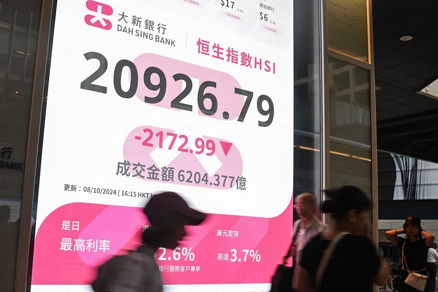 Pedestrians walk past a sign showing the numbers of the Hang Seng Index in Hong Kong on 8 October 2024. (Peter Parks/AFP)