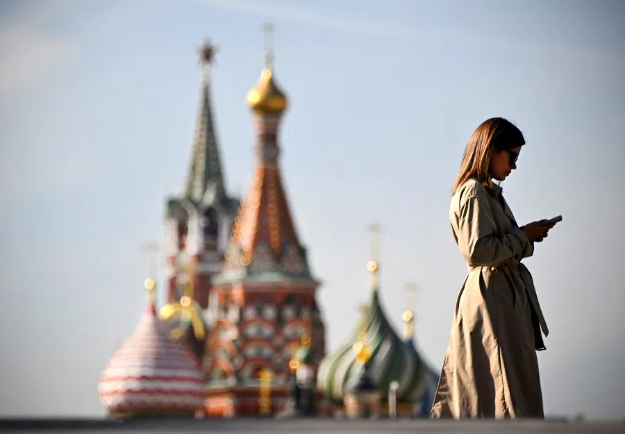 A woman walks in front of the Kremlin’s Spasskaya tower (L) and St. Basil’s cathedral in downtown Moscow, on 23 September 2024.