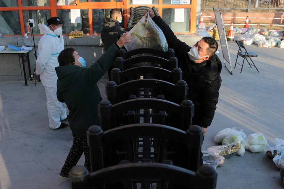 A worker delivers food supplies to residents at a residential compound under lockdown in Xi'an, Shaanxi province, China, 29 December 2021. (CNS photo via Reuters)