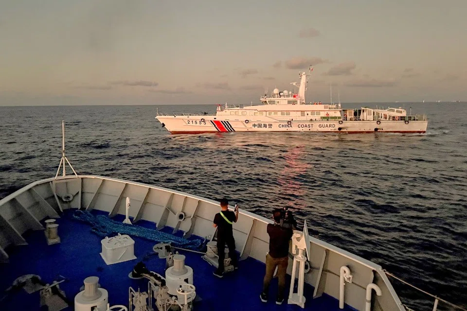 Members of the media take footage of a Chinese Coast Guard vessel blocking a Philippine Coast Guard vessel on its way to a resupply mission at Second Thomas Shoal in the South China Sea on 5 March 2024. (Adrian Portugal/Reuters)