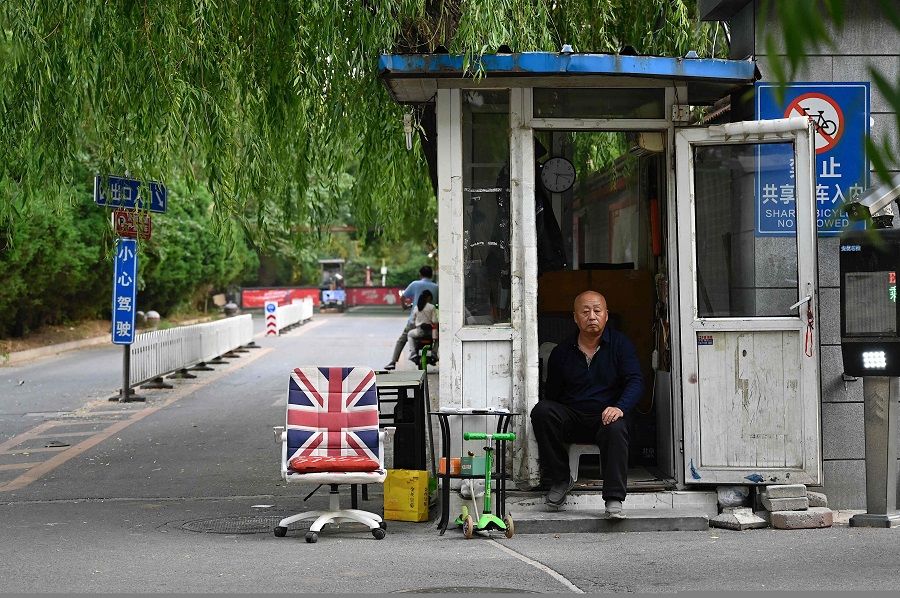 A security guard sits at the entrance of a residential compound in Beijing, China, on 14 May 2023. (Jade Gao/AFP)