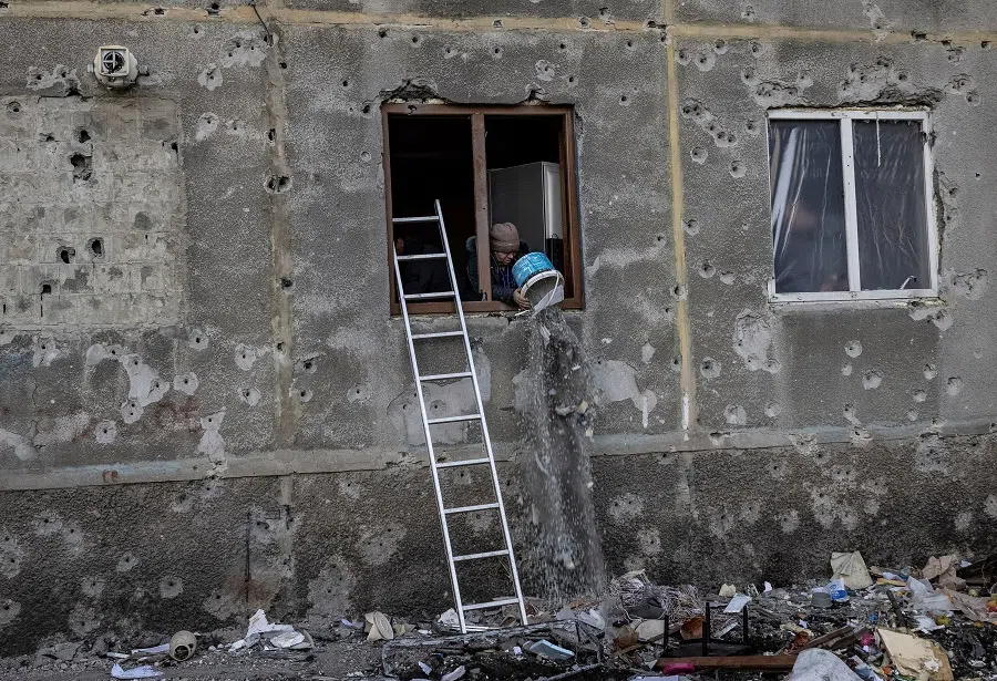 A woman throws debris out of her apartment’s window which was damaged by a Russian missile strike, amid Russia’s attack on Ukraine, in the town of Dobropillia, Donetsk region, Ukraine, on 8 March 2025. (Nadia Karpova/Reuters)