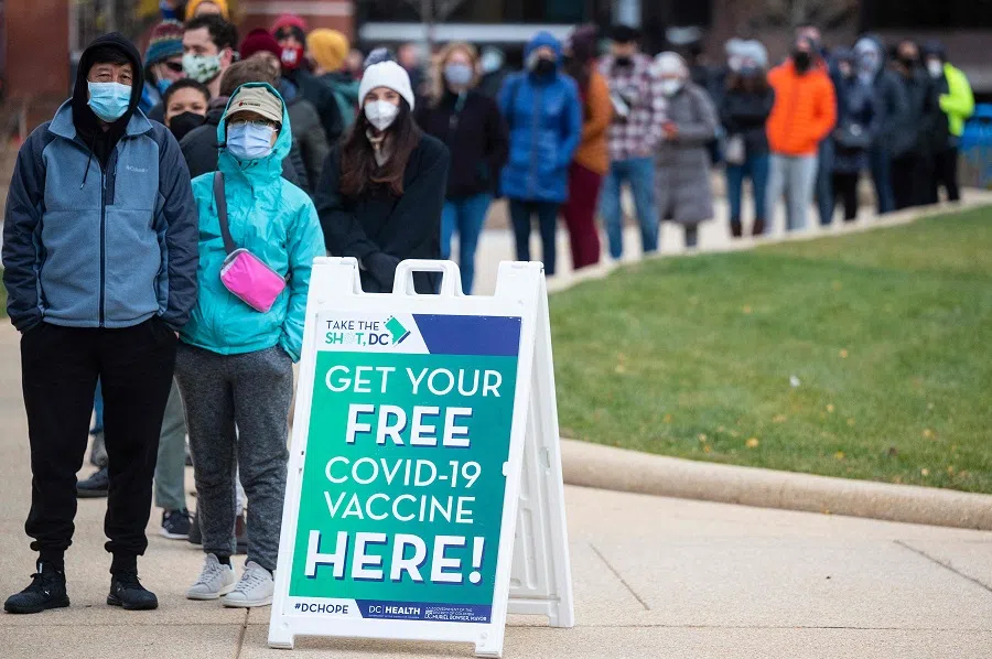 In this file photo taken on 29 November 2021, people wait in line at a walk-up vaccination site in Washington, DC, US. (Jim Watson/AFP)