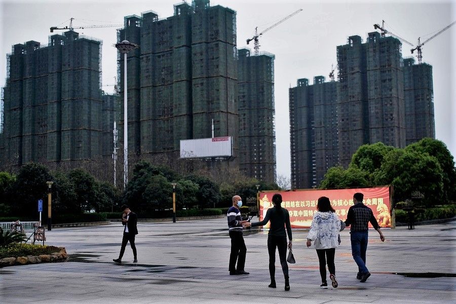 People with face masks are seen at a square near residential buildings under construction in Xianning, Hubei, China, on 25 March 2020. (Aly Song/Reuters)