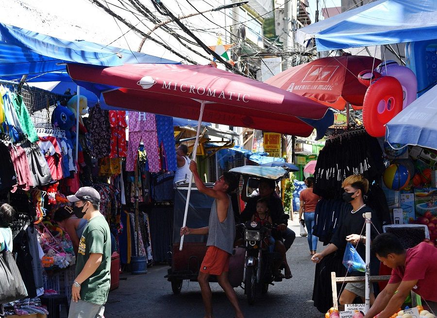 A vendor arranges a parasol at a popular shopping street in Manila on 2 April 2024.  (Ted Aljibe/AFP)