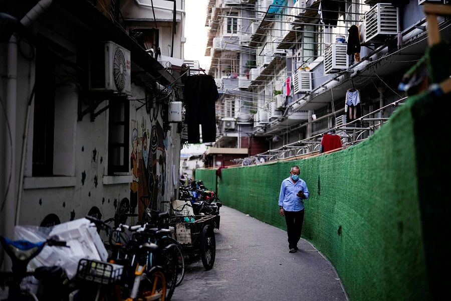 A man walks along barriers at a residential area in Shanghai, China, 15 June 2022. (Aly Song/Reuters)