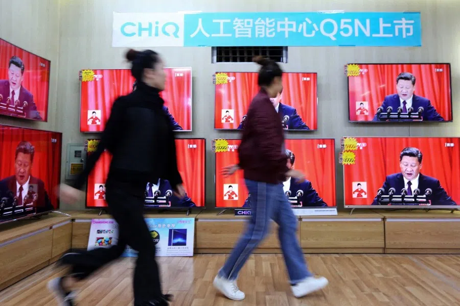 In this file photo taken on 18 October 2017, people walk past television screens showing China's President Xi Jinping as he delivers a speech during the opening of the 19th Communist Party Congress in Rongan in China's southern Guangxi region. (AFP)