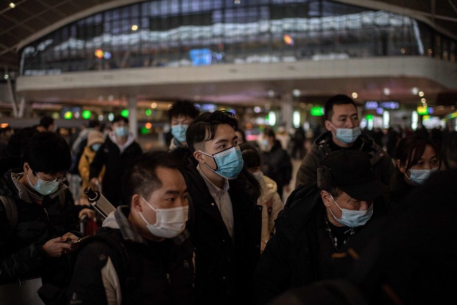 People wearing face masks wait to board a train at the main railway station in Wuhan, China, on 10 January 2021. (Nicolas Asfouri/AFP)