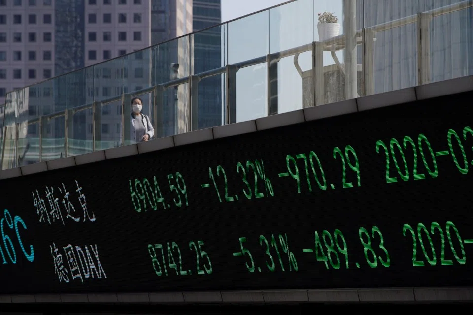 A pedestrian wearing a face mask walks on an overpass with an electronic board showing stock information, following an outbreak of the coronavirus disease (COVID-19), at Lujiazui financial district in Shanghai, March 2020. (Aly Song/REUTERS)