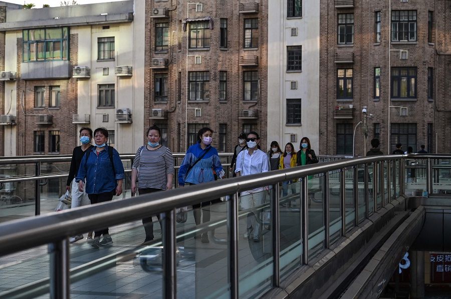 People walk on a bridge in the district of Huangpu in Shanghai, China, on 22 October 2022. (Hector Retamal/AFP)