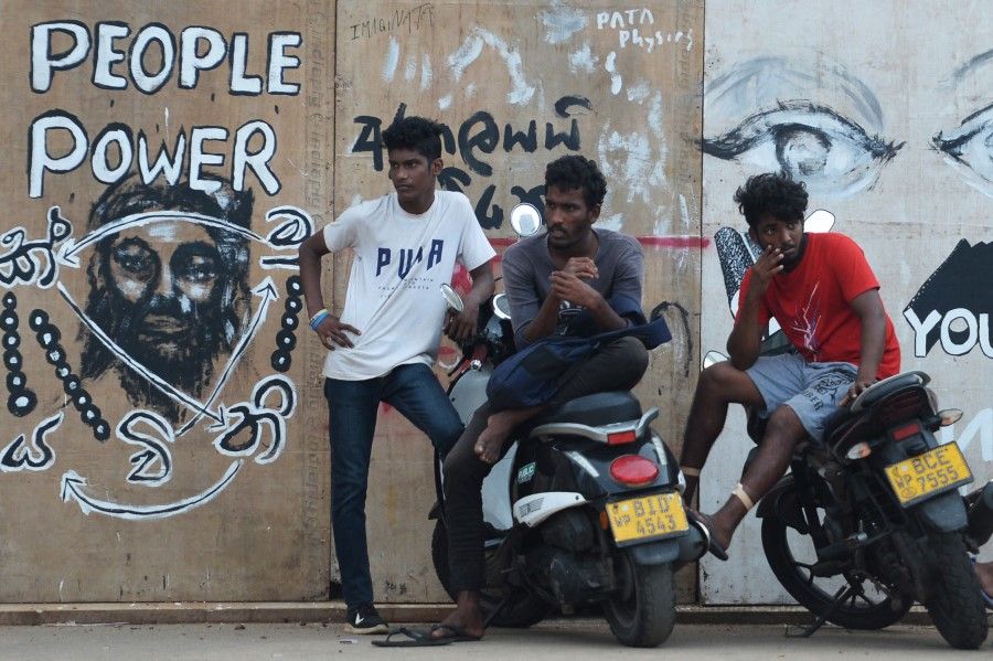 People beside a mural near Presidential Secretariat in Colombo on 23 July 2022. (Arun Sankar/AFP)