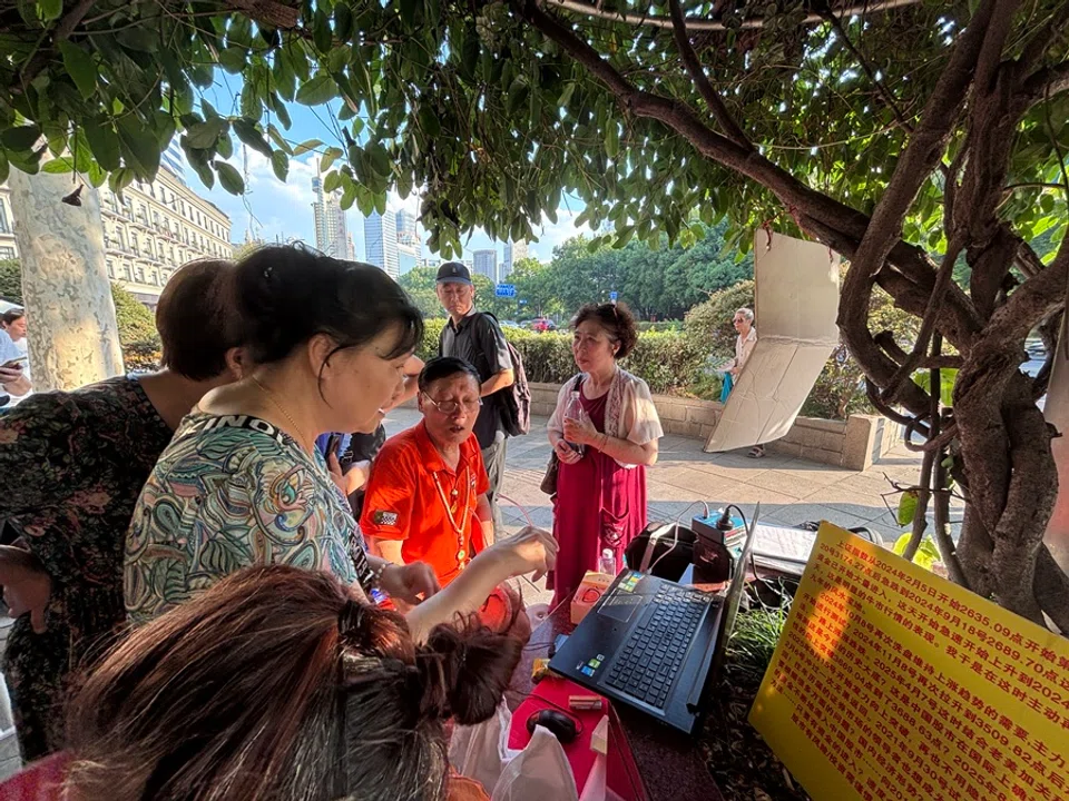Stock traders gather around veteran Shanghai stock trader Feng Baofu (second from right, in a red top) with their questions regarding the stock market on 23 August 2025.