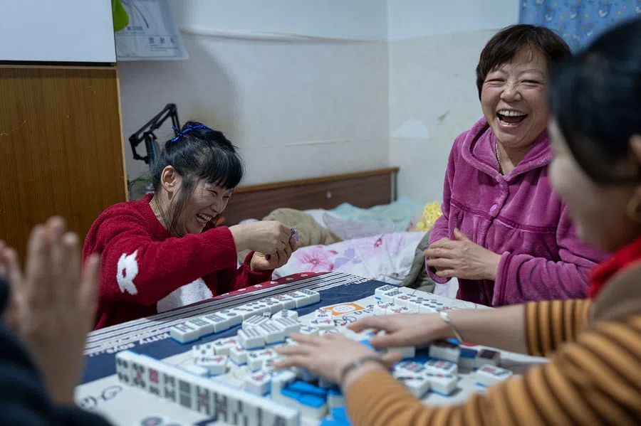 Sister Chen playing mahjong at a friend’s rented home, with poker cards as chips rather than real money, which does not dampen the fun. 