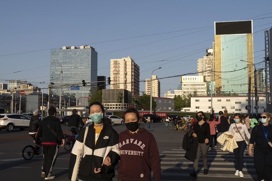 Pedestrians wearing protective masks cross a road in the Dongdaqiao area of Beijing, China, on 23 April 2020. (Giulia Marchi/Bloomberg)