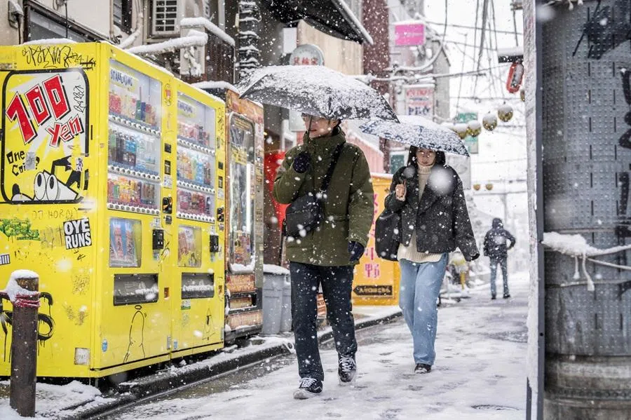 People walk down a street during a snowfall in Tokyo on 8 February 2026. (Yuichi Yamazaki/AFP)