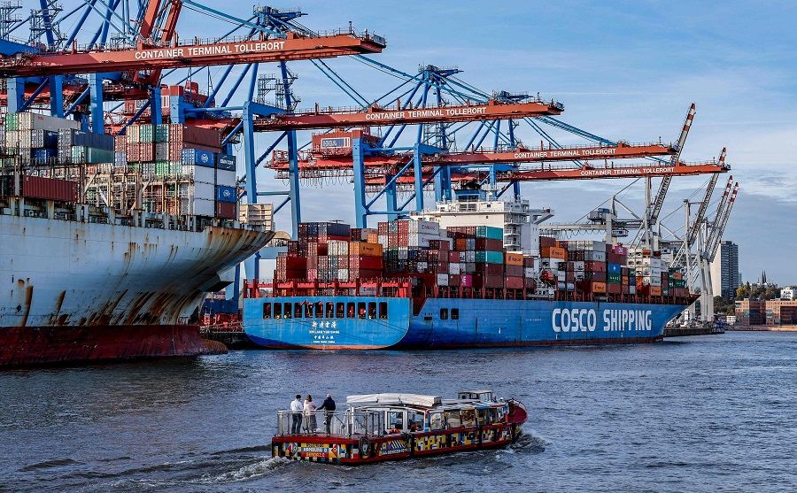 A small boat passes in front of the container ship 'COSCO Pride' (far left) and 'Xin Lian Yun Gang' of China COSCO Shipping Corporation are unloaded at the Tollerort Container Terminal owned by HHLA, in the harbour of Hamburg, Germany, 26 October 2022. (Axel Heimken/AFP)