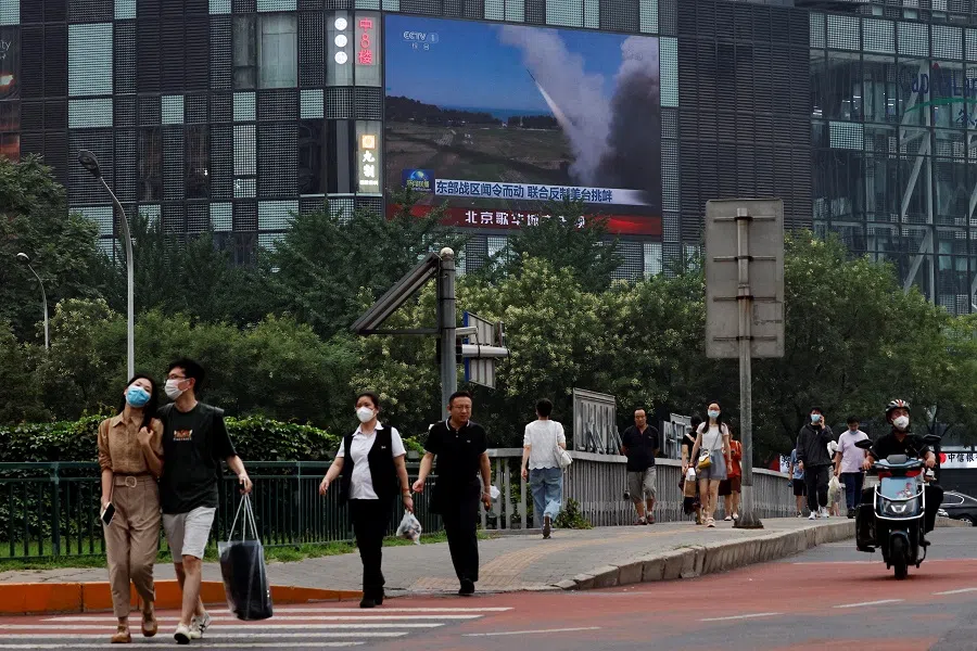 Pedestrians walk past a giant screen broadcasting a news report on the Chinese People's Liberation Army's (PLA) military exercises around Taiwan, in Beijing, China, 4 August 2022. (Thomas Peter/Reuters)