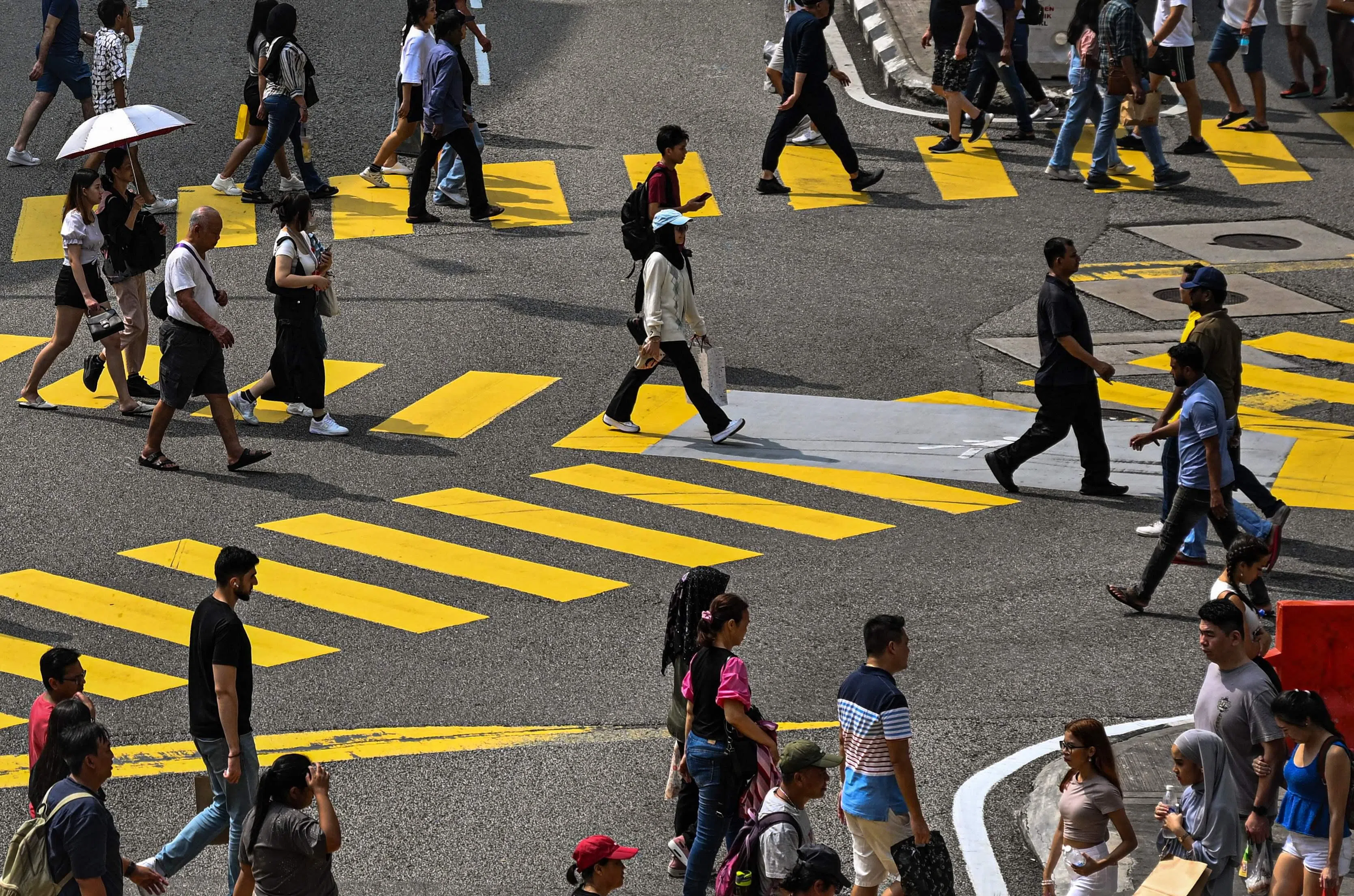 Pedestrians crossing a road in Kuala Lumpur on 24 April 2024.