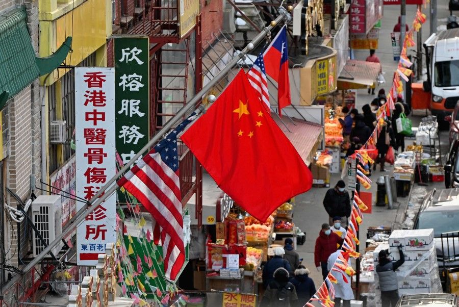 A Chinese flag hangs between American flags in Chinatown on 17 February 2021 in New York City. (Angela Weiss/AFP)