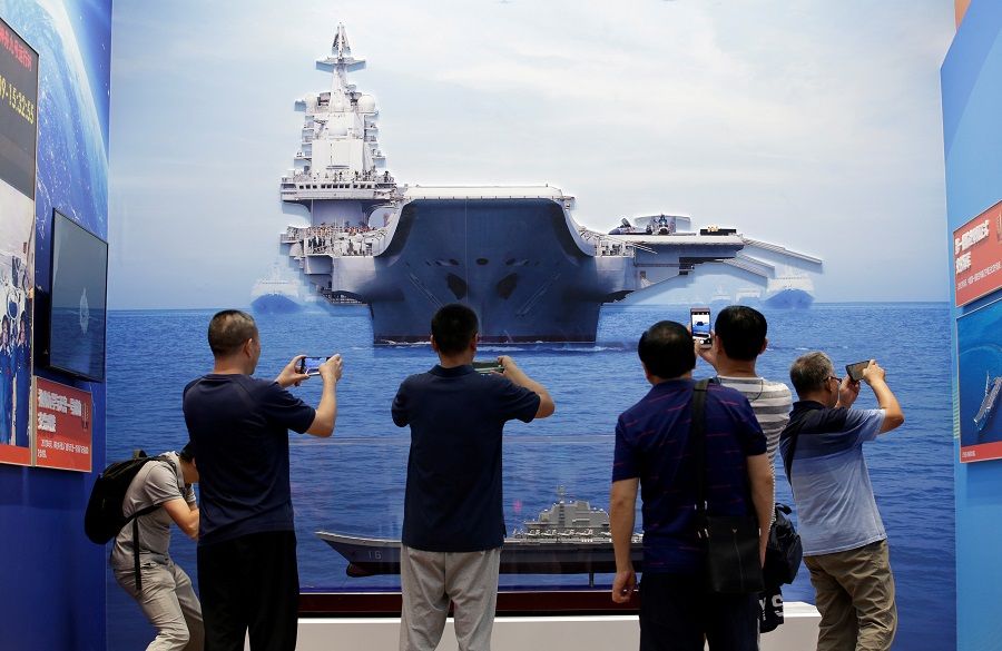 In this file photo taken on 24 September 2019, visitors hold their mobile phones in front of exhibits showing the People's Liberation Army Navy's first aircraft carrier Liaoning, during an exhibition on China's achievements marking the 70th anniversary of the founding of the People's Republic of China at the Beijing Exhibition Center, in Beijing, China. (Jason Lee/File Photo/Reuters)