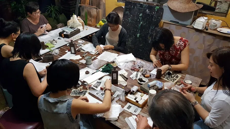 Young seal carvers learning the art of engraving characters on hard surfaces.