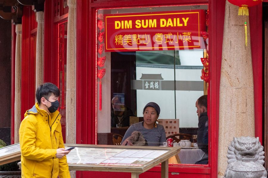 A pedestrian wears a surgical face mask as he passes a food vendor in London's Chinatown district on 4 February 2020. As the deadly Covid-19 spreads worldwide, Asian communities around the world are finding themselves subject to suspicion and fear. (Justin Tallis/AFP)