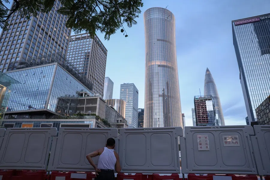 A man looks through barriers at a construction site near office buildings in Shenzhen, Guangdong province, China, 15 September 2025. (Tingshu Wang/Reuters)