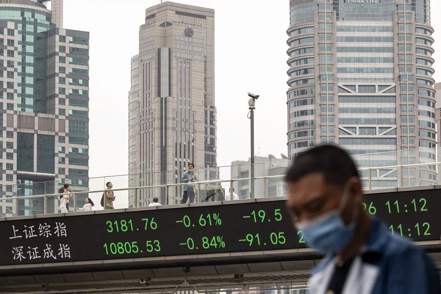 Pedestrians along an elevated walkway as an electronic ticker displays stock figures in Pudong's Lujiazui Financial District in Shanghai, China, on 26 May 2023. (Qilai Shen/Bloomberg)