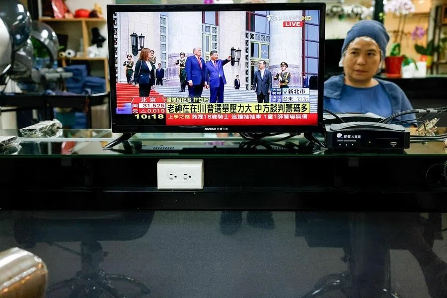 A person watches a live television broadcast of a meeting between US President Donald Trump and Chinese President Xi Jinping at a hair salon in Taipei, Taiwan, on 14 May 2026. (Ann Wang/Reuters)