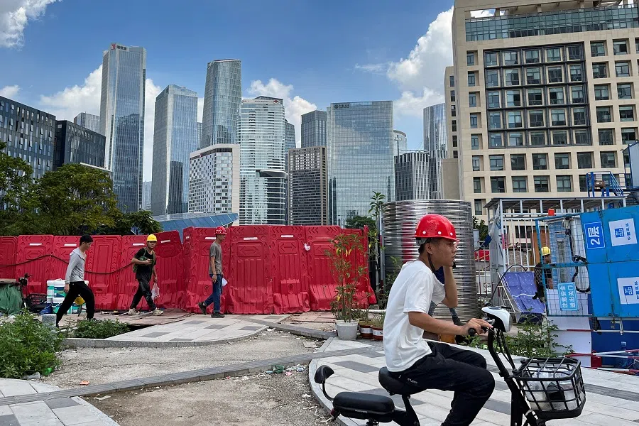 Workers walk past an under-construction area with completed office towers in the background, in Shenzhen's Qianhai new district, Guangdong province, China, on 25 August 2023. (David Kirton/Reuters)