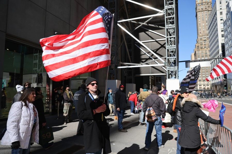 A man holds a US flag in front of Trump Tower on 8 March 2021 in New York City. (Spencer Platt/AFP)