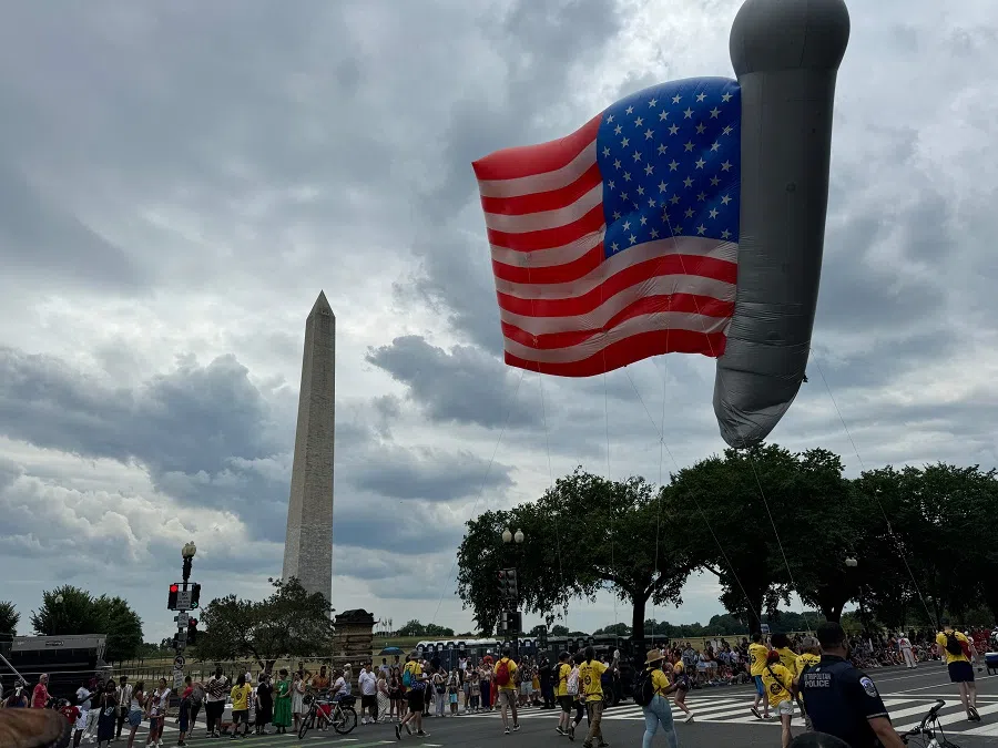 People pass the Washington Monument as they take part in a parade during celebrations marking Independence Day on 4 July 2024 in Washington, DC. (Daniel Slim/AFP)