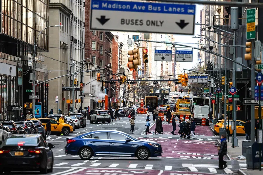 People cross the street while cars pass by Madison Avenue in the Manhattan borough of New York on 14 January 2024. (Charly Triballeau/AFP)