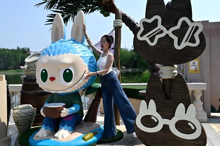 This picture taken on 18 June 2025 shows a woman posing for a picture next to the character Labubu as she visits Pop Mart’s theme park Pop Land in Beijing, China.