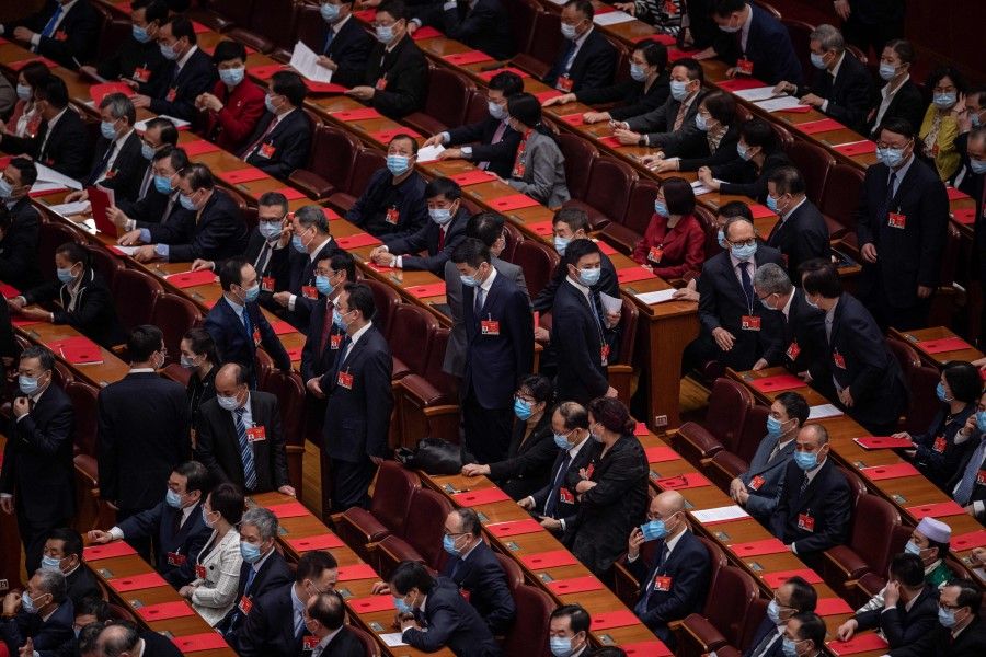 Delegates chat inside the Great Hall of the People before the closing session of the National People's Congress at the Great Hall of the People in Beijing on 11 March 2021. (Nicolas Asfouri/AFP)