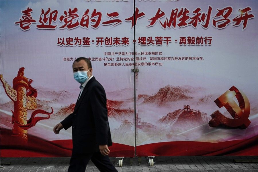 A man walks past a propaganda poster welcoming the 20th Party Congress, along a street in Beijing on 21 September 2022. (Jade Gao/AFP)