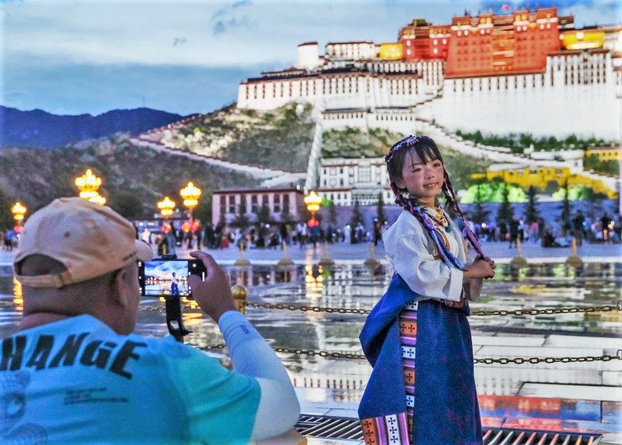 A parent takes a photograph of her child in traditional Tibetan clothing as she poses outside Potala palace in Lhasa, Tibet, on 27 June 2023. (CNS)