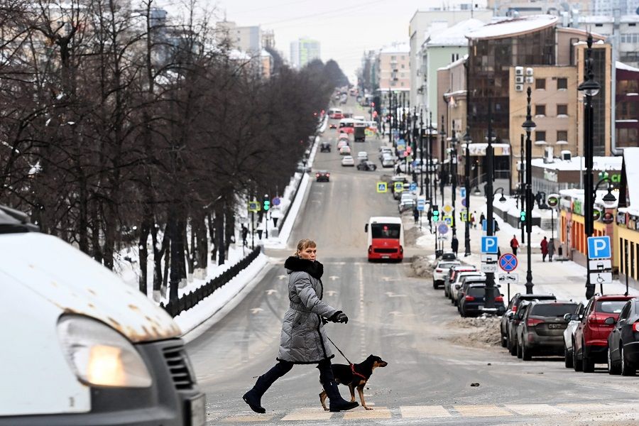 A woman with a dog crosses a street in Perm, Russia, on 27 January 2021. (Kirill Kudryavtsev/AFP)