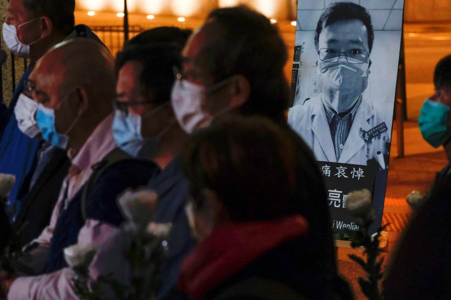 People wearing masks attend a vigil for late Li Wenliang, an ophthalmologist who died of coronavirus at a hospital in Wuhan. (Tyrone Siu/Reuters)
