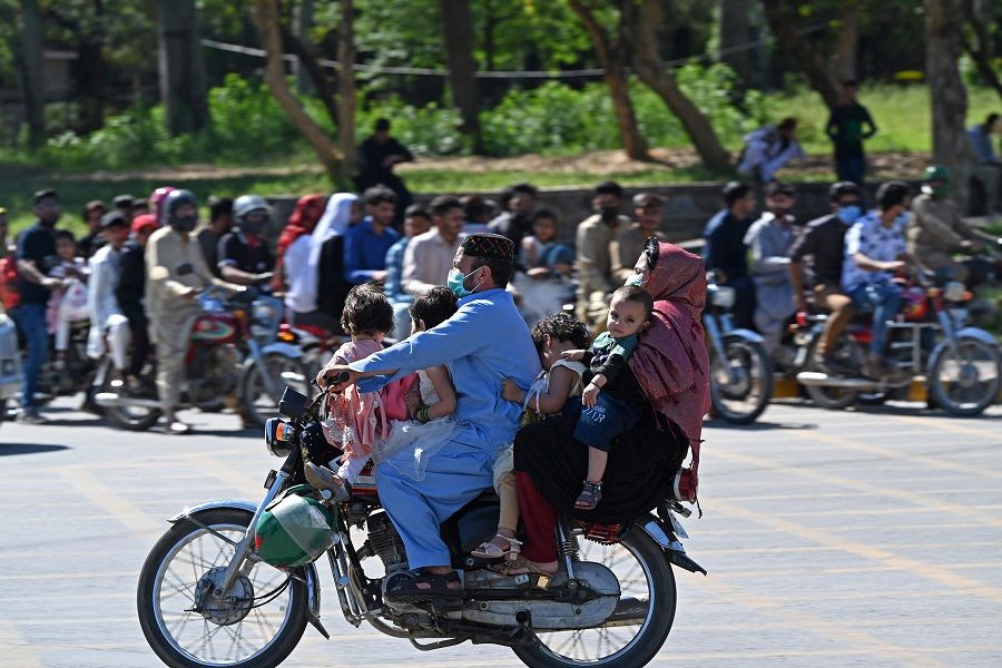A family arrives on a two-wheeler to visit the grand Faisal Mosque during the second day of the Eid al-Fitr celebrations, in Islamabad, Pakistan, on 23 April 2023. (Farooq Naeem/AFP)