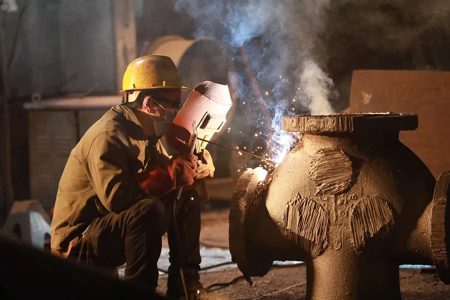 A worker welds a piece of steel machinery at a machinery manufacturing company which produces for export in Hangzhou, in China’s eastern Zhejiang province, on 5 March 2025. (AFP)