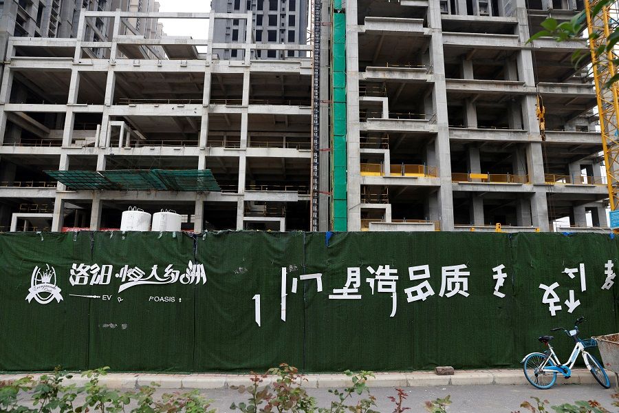 A peeling logo of the Evergrande Oasis, a housing complex developed by Evergrande Group, is seen outside the construction site where the residential buildings stand unfinished, in Luoyang, China, 16 September 2021. (Carlos Garcia Rawlins/File Photo/Reuters)
