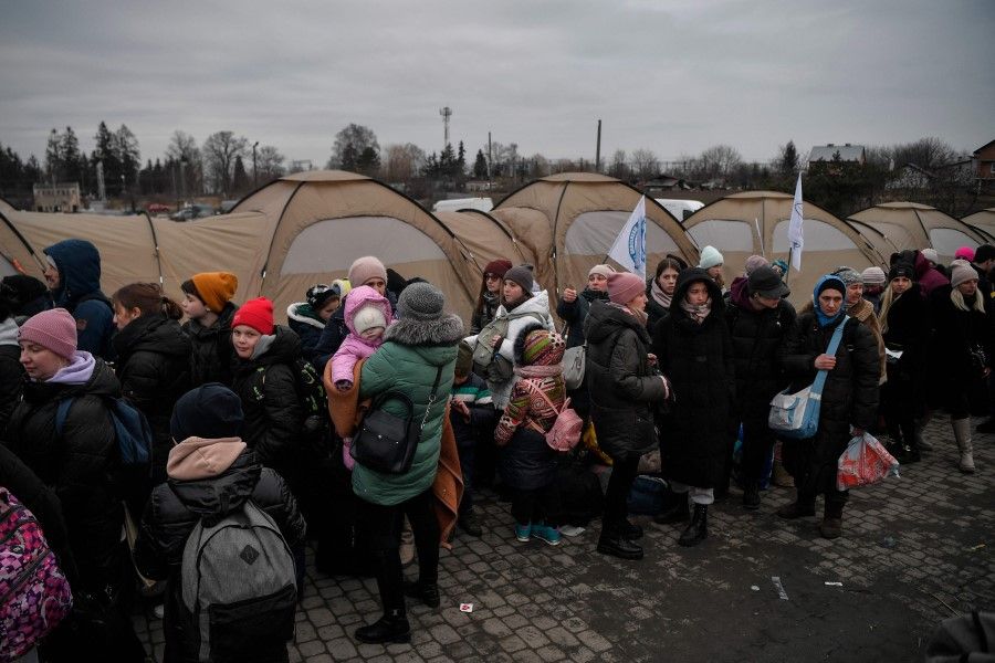 Refugees wait to be transported after crossing the Ukrainian-Polish border at the border crossing in Medyka, southeastern Poland, on 9 March 2022. (Louisa Gouliamaki/AFP)