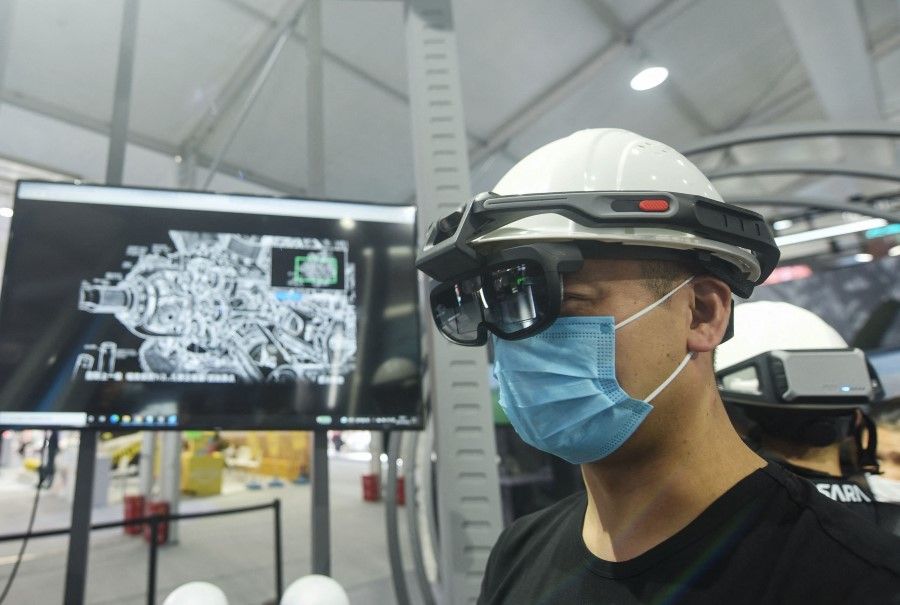 A visitor tries a pair of virtual reality (VR) glasses as he watches a digital engine during the Apsara Conference, a cloud computing and artificial intelligence (AI) conference, in Hangzhou, in China's eastern Zhejiang province on 19 October 2021. (STR/AFP)