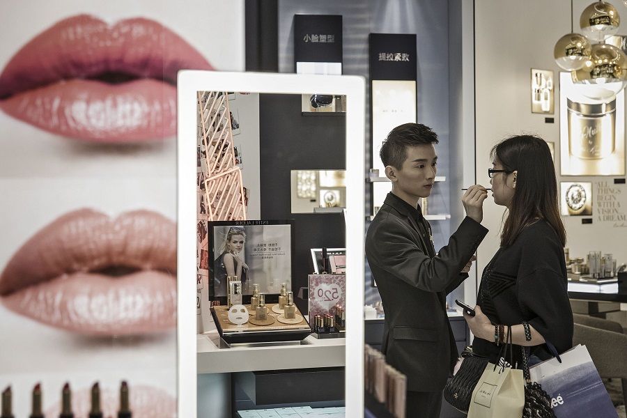 A sales assistant helps a customer try on a lip colour at an Estee Lauder store in the Raffles City shopping mall in Shanghai, China, on 31 May 2017. (Qilai Shen/Bloomberg)