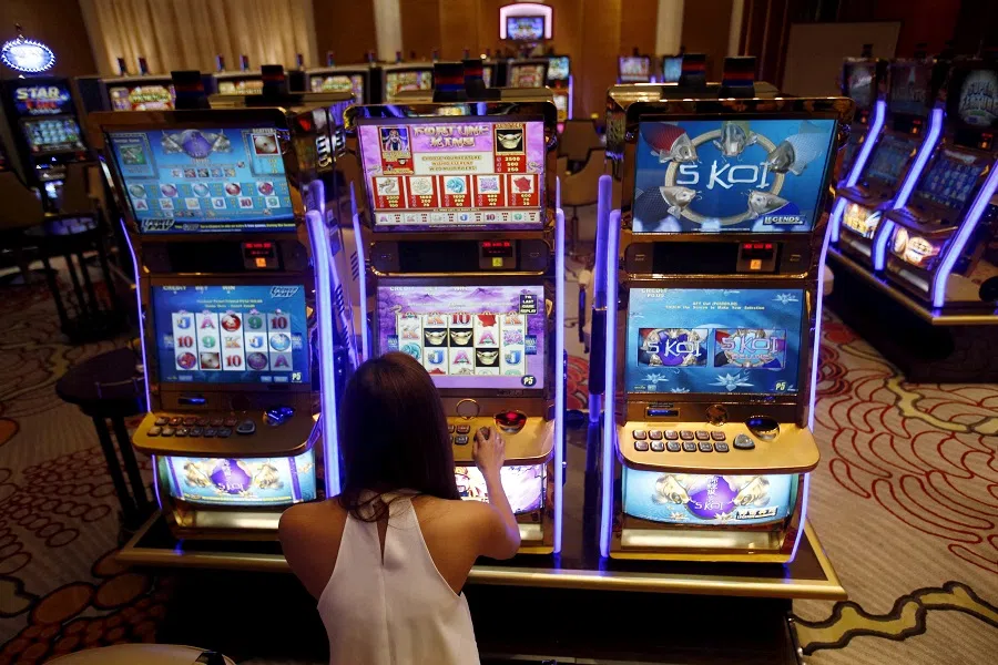 A casino trainee demonstrates how to play a slot machine in the Philippines, on 16 April 2015. (Erik De Castro/Reuters)