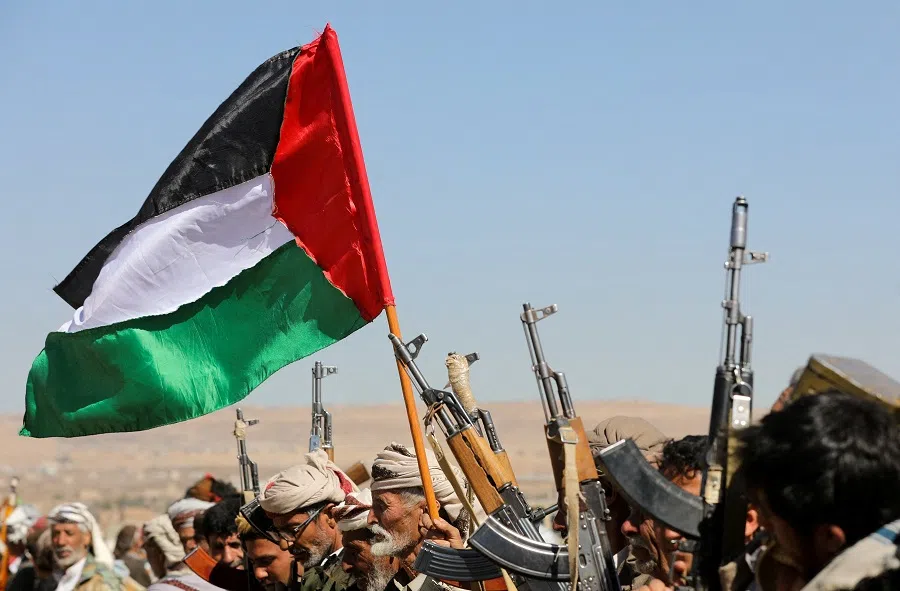 Tribal supporters of Yemen's Houthis wave a Palestinian flag and hold up their firearms during a protest against recent US-led strikes on Houthi targets, near Sanaa, Yemen, on 14 January 2024. (Khaled Abdullah/Reuters)