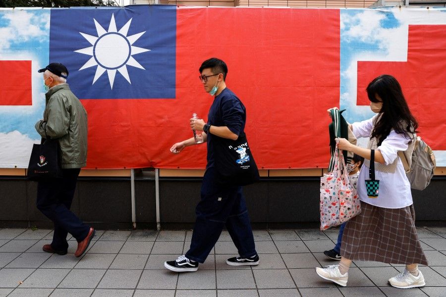 People walk past a Taiwan flag in Taipei, Taiwan, 7 March 2023. (Ann Wang/Reuters)