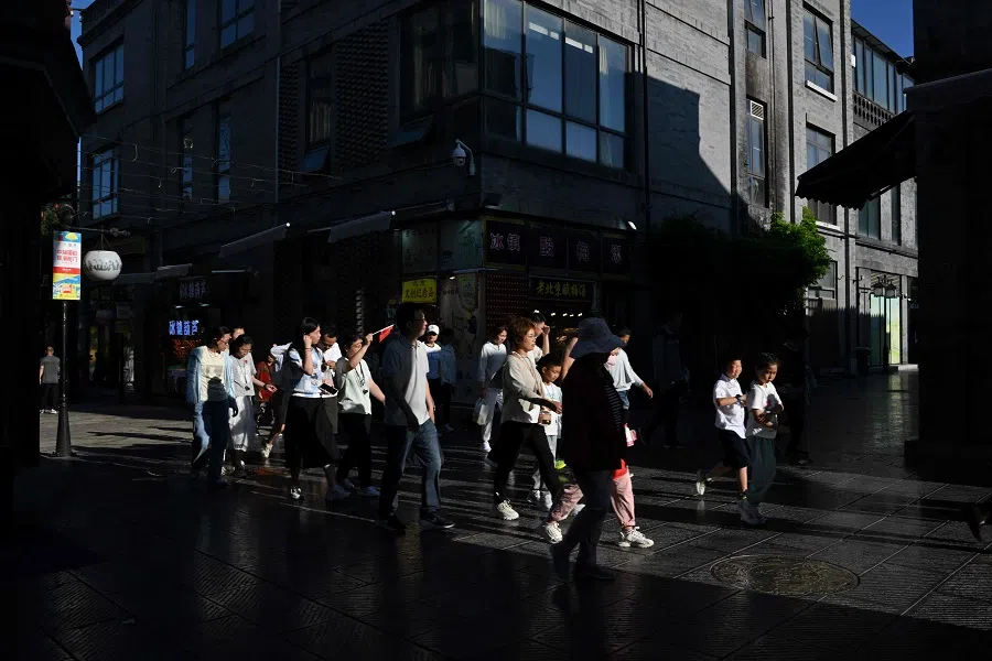 People walk around the Qianmen promenade in Beijing on 21 June 2025. (Adek Berry/AFP)